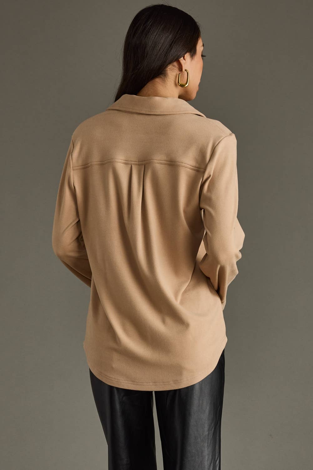 Person wearing a beige jacket on a gray background
