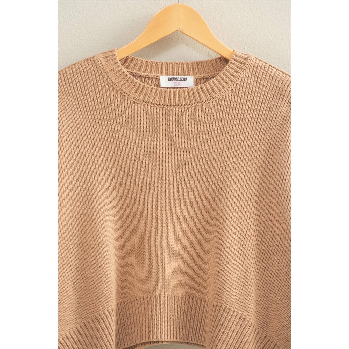 Beige sweater on a hanger against a white background