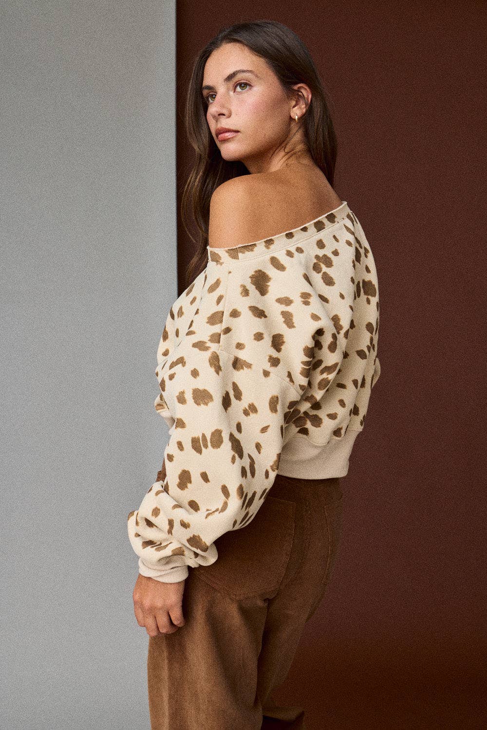Woman wearing a leopard print off-shoulder top against a gradient wall.
