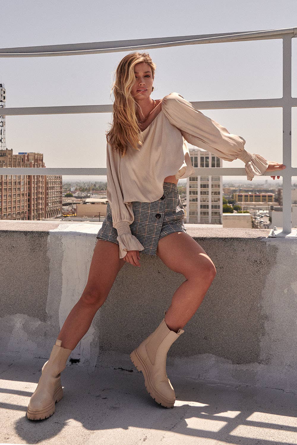 Woman posing on a rooftop with a cityscape in the background
