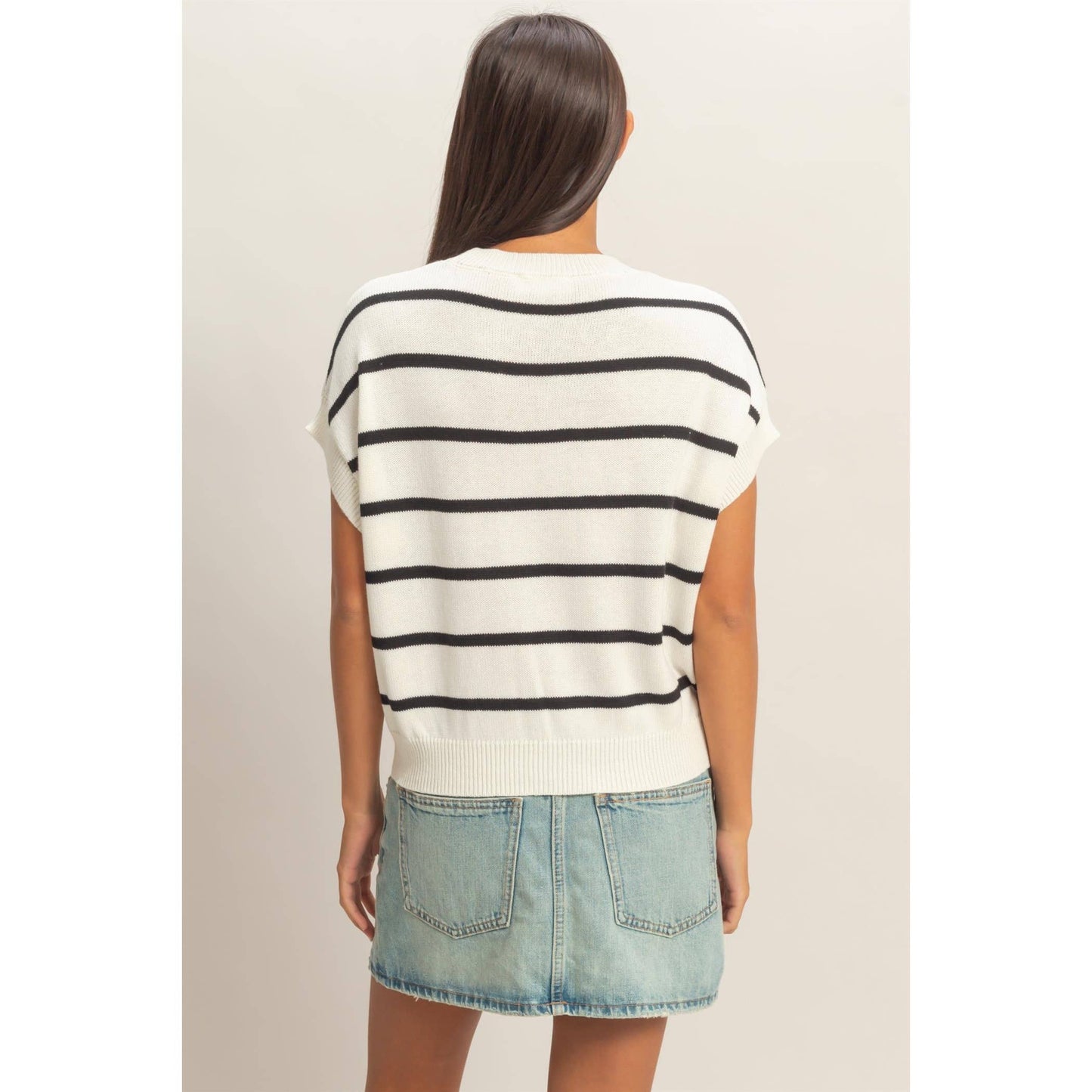 Woman wearing a striped shirt and denim skirt on a plain background