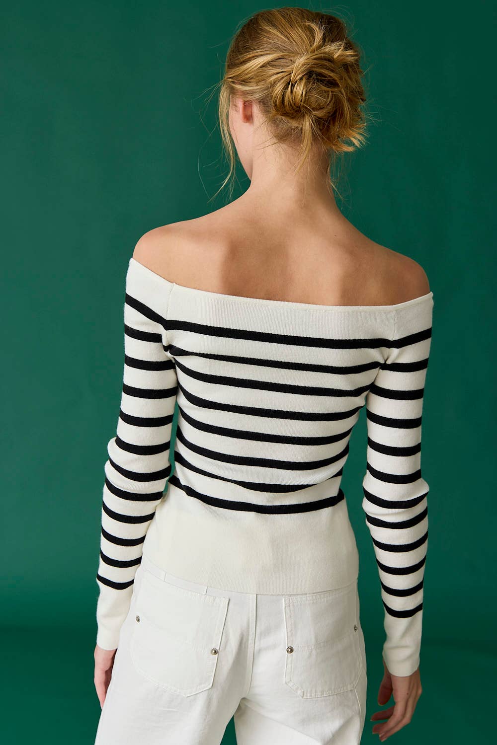 Person wearing a black and white striped off-shoulder top against a green background
