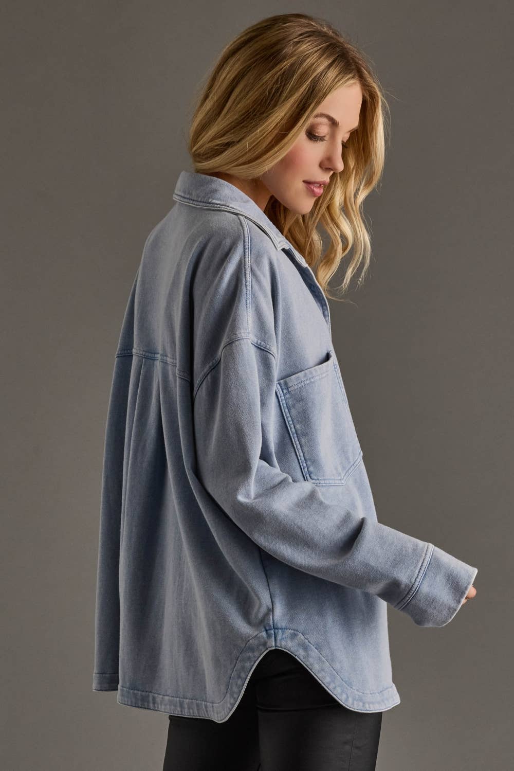 Woman wearing a light blue denim jacket against a gray background