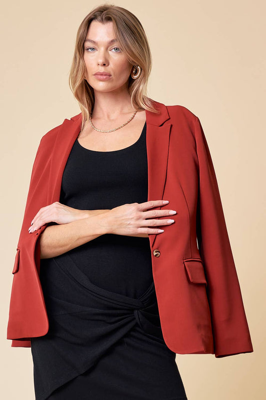 Woman wearing a red blazer over a black dress on a beige background