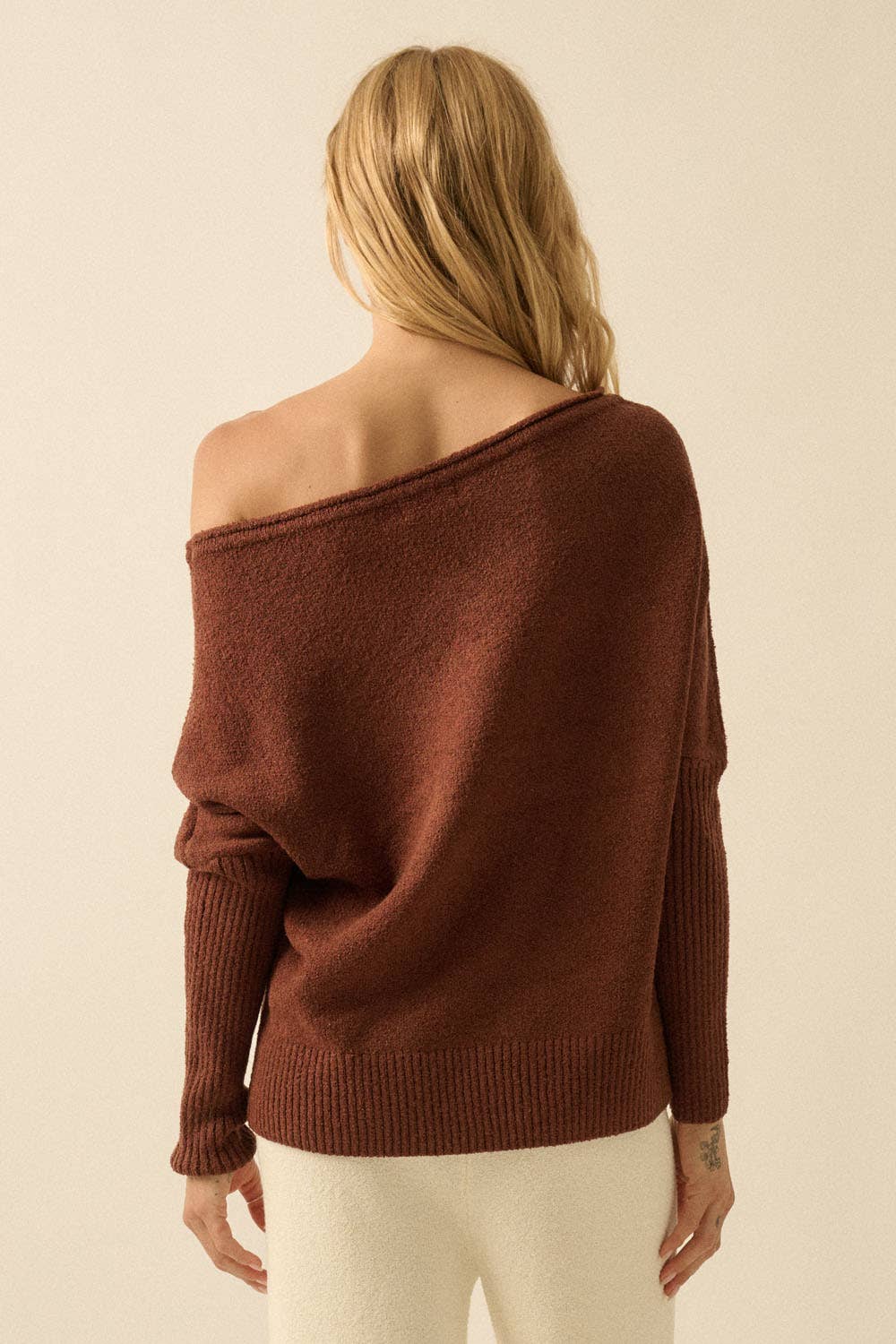 Brown off-shoulder sweater worn by a person on a beige background