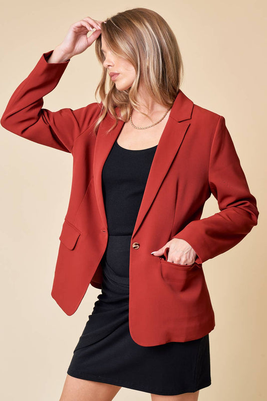 Woman wearing a red blazer over a black top and skirt on a beige background