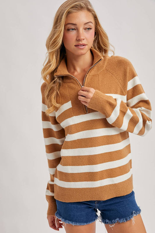 Woman wearing a brown and white striped sweater with denim shorts on a plain background