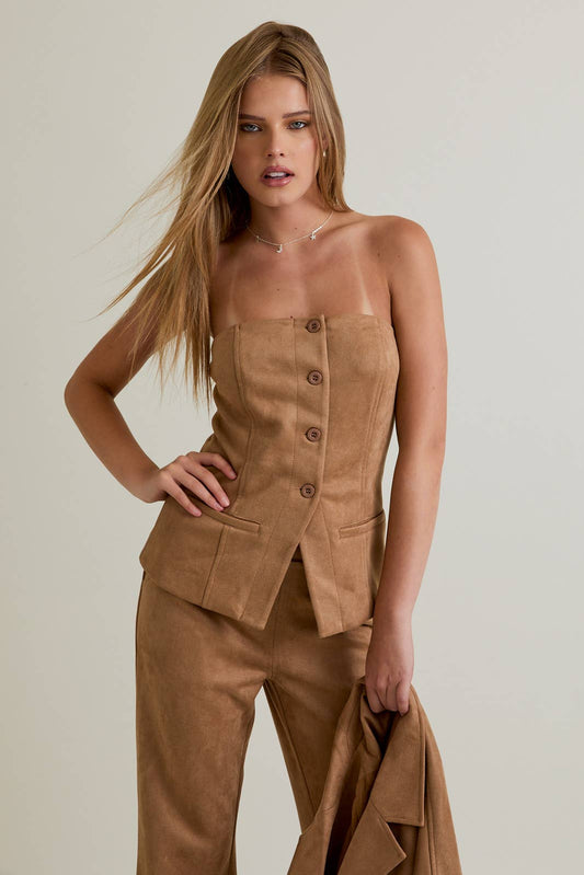 Woman wearing a suede top with a plain background