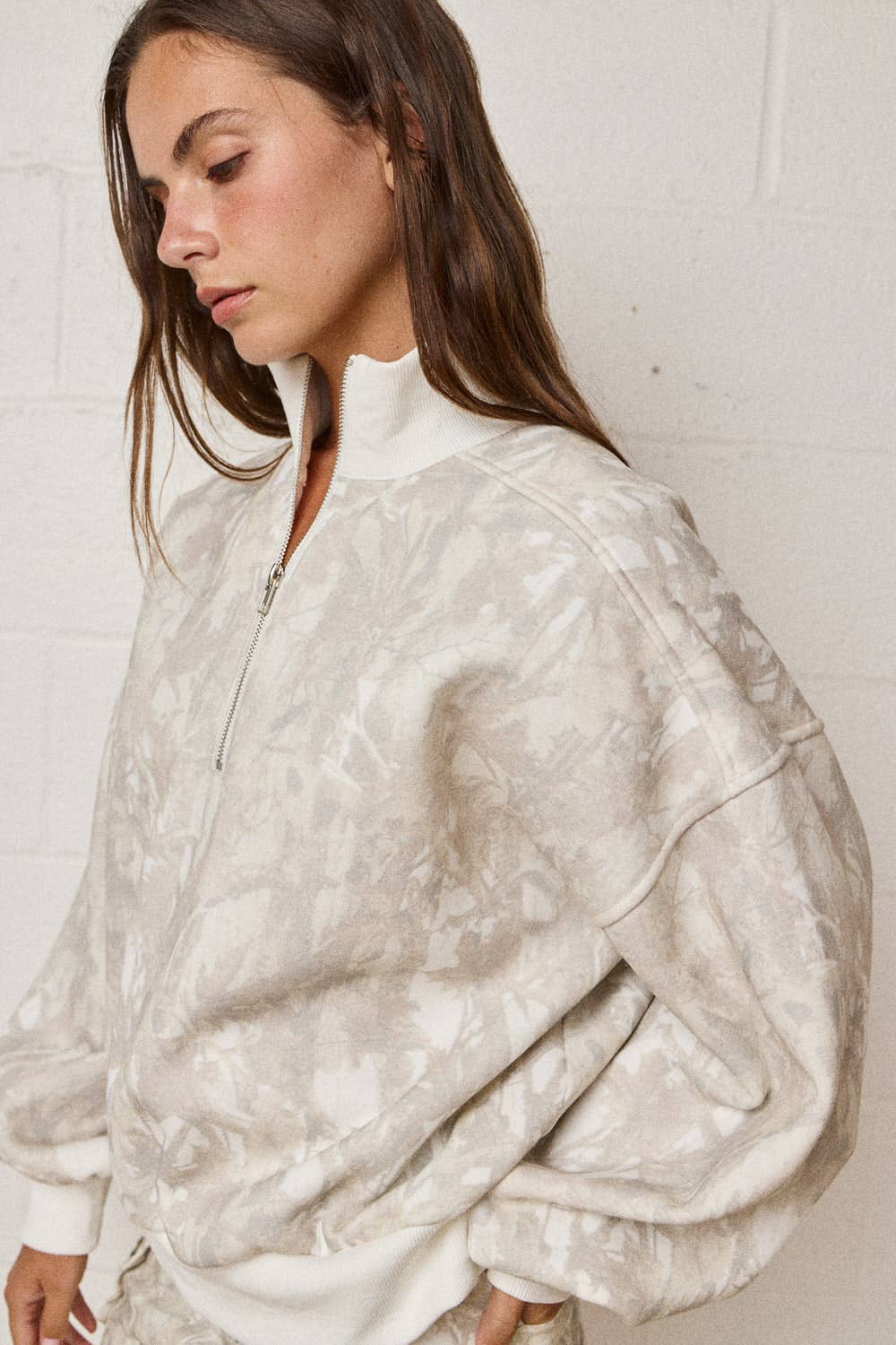 Woman wearing a white patterned jacket against a plain background