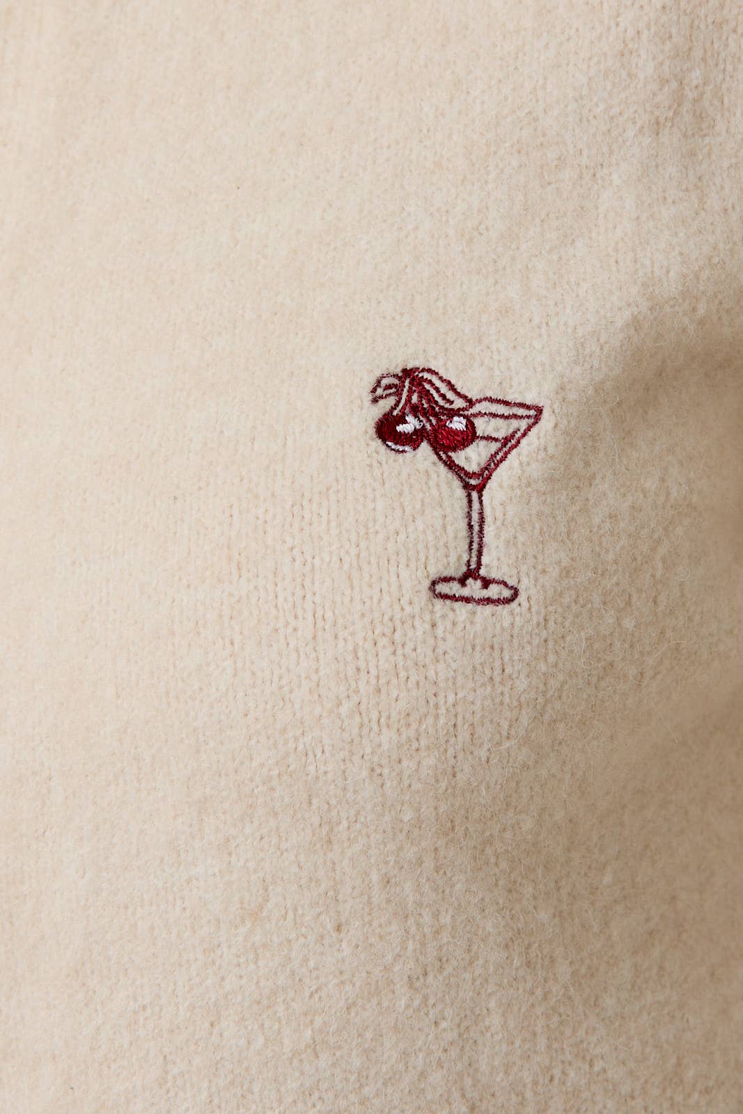 Embroidered martini glass with cherry on a beige fabric background