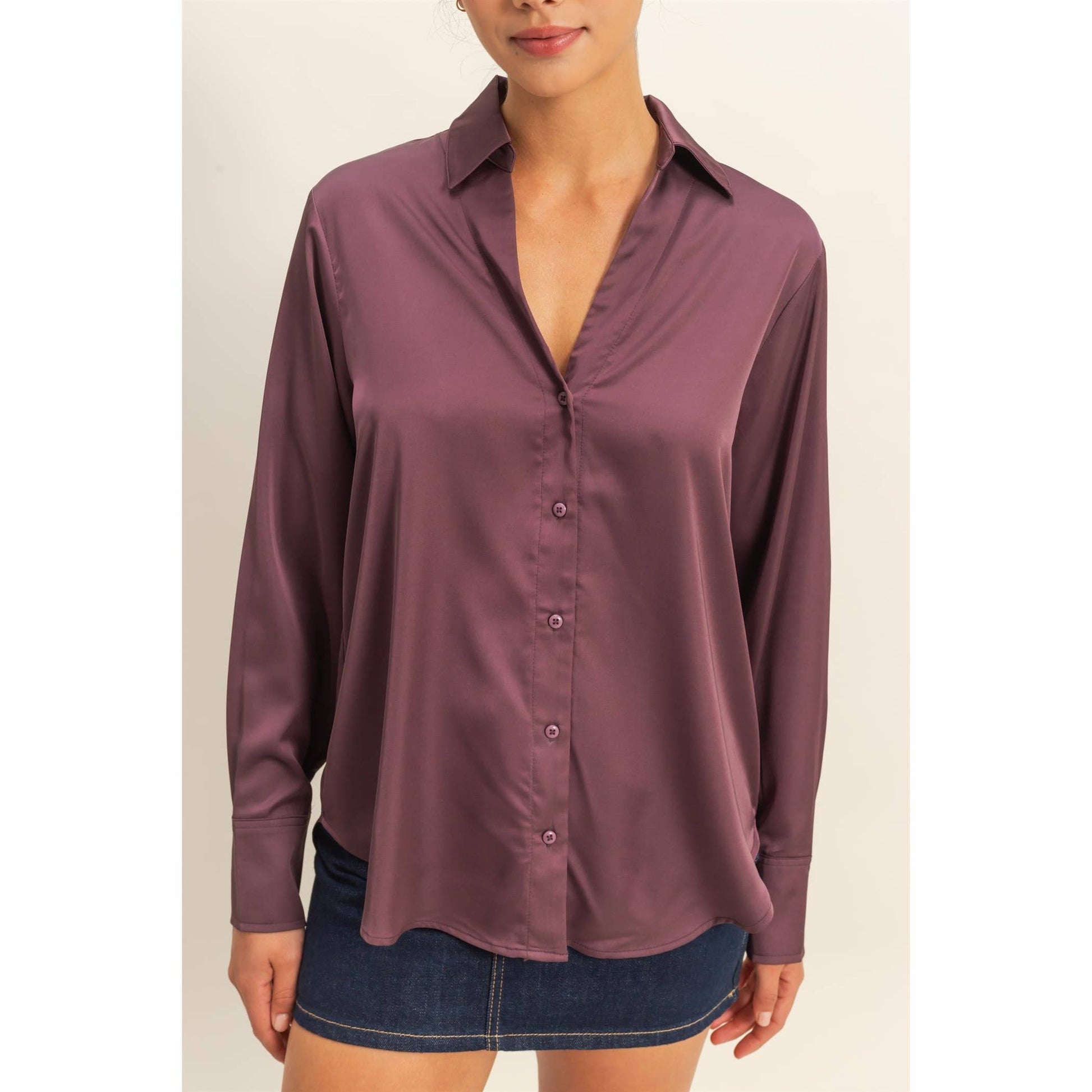 Woman wearing a purple button-up shirt with a plain background
