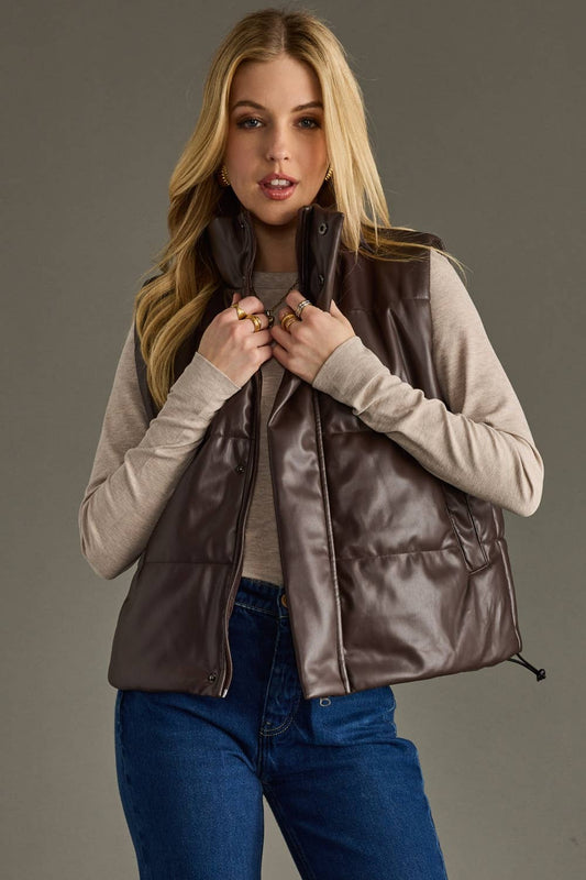 Woman wearing a brown vest over a beige sweater on a gray background
