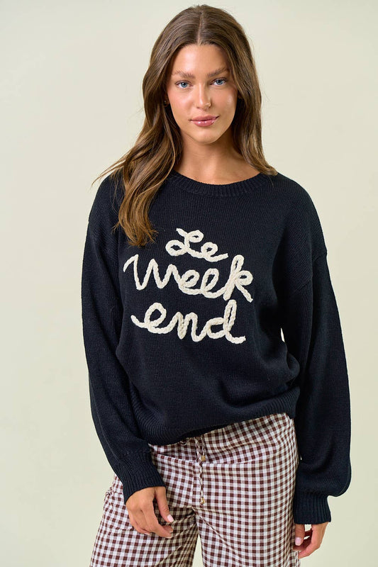 Woman wearing a navy sweater with 'Le Week End' text on a beige background