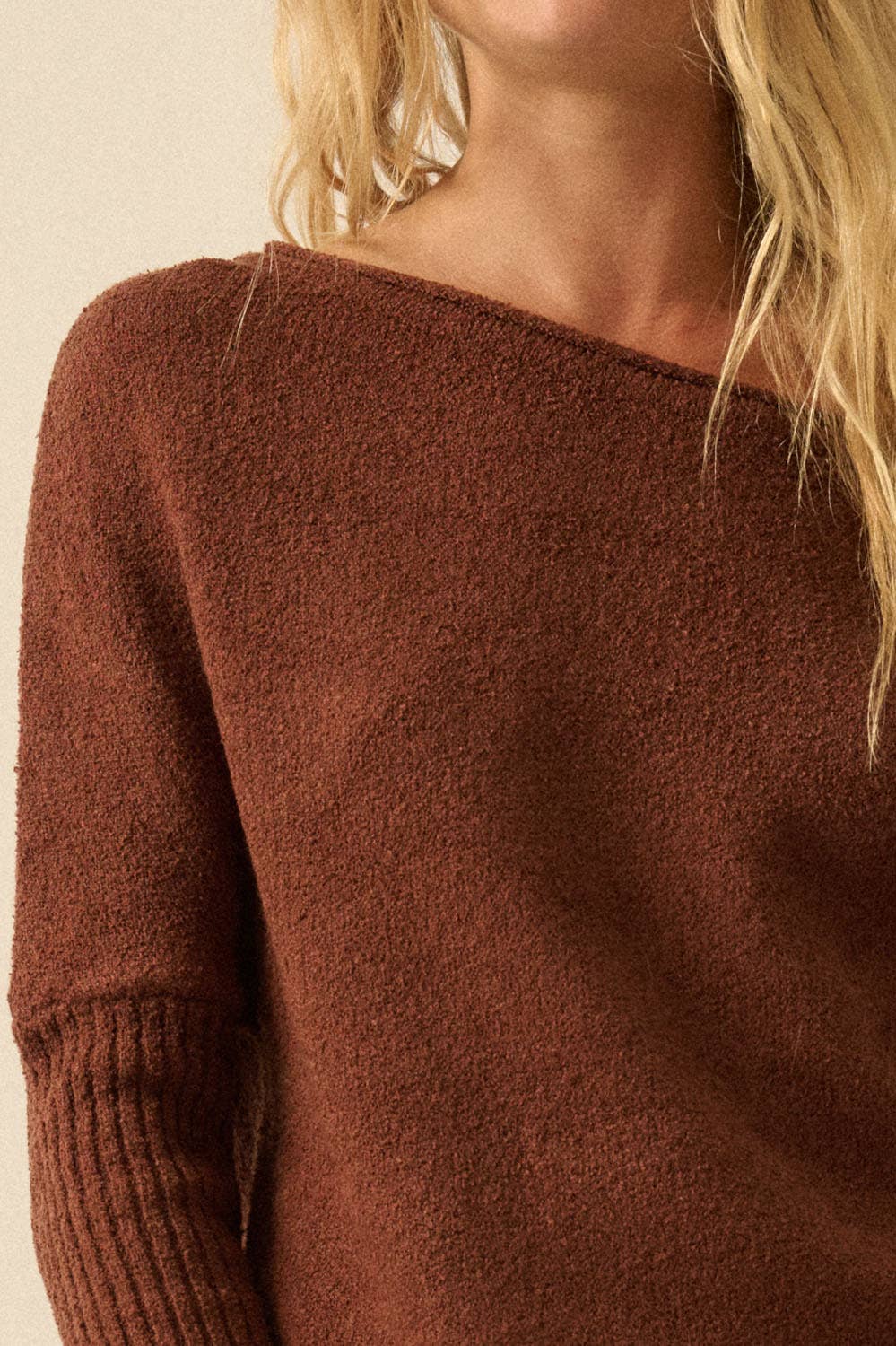 Close-up of a brown sweater worn by a person with blonde hair.