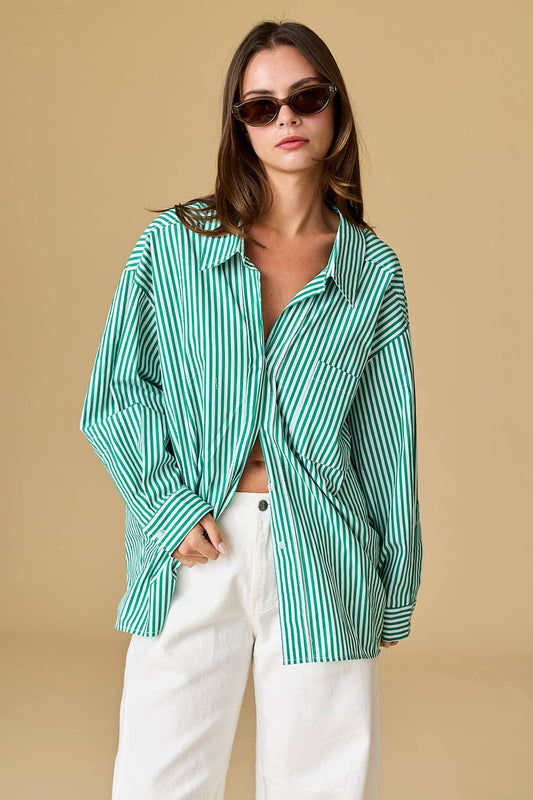 Woman wearing a green and white striped shirt with white pants on a beige background