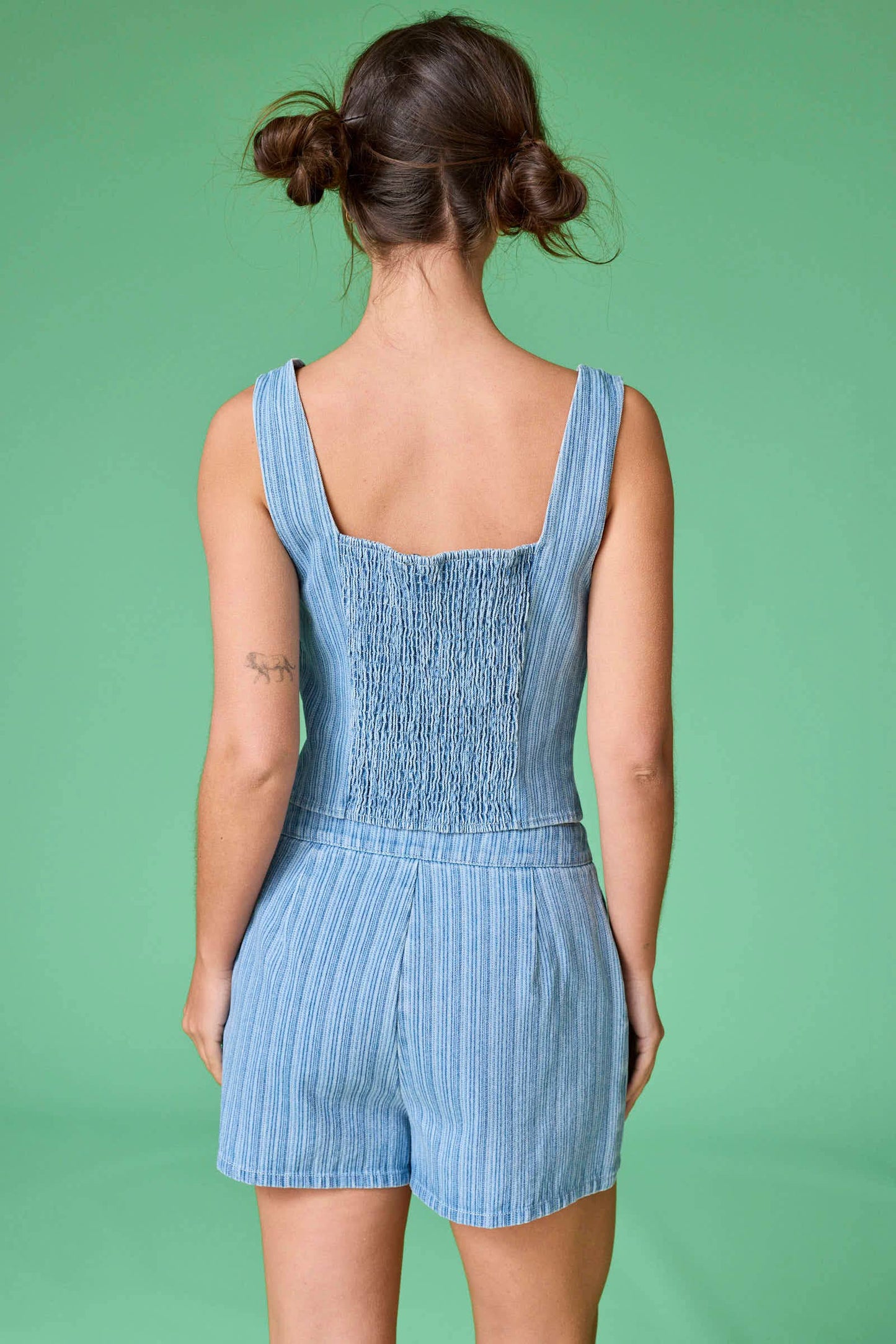 Person wearing a blue striped romper against a green background