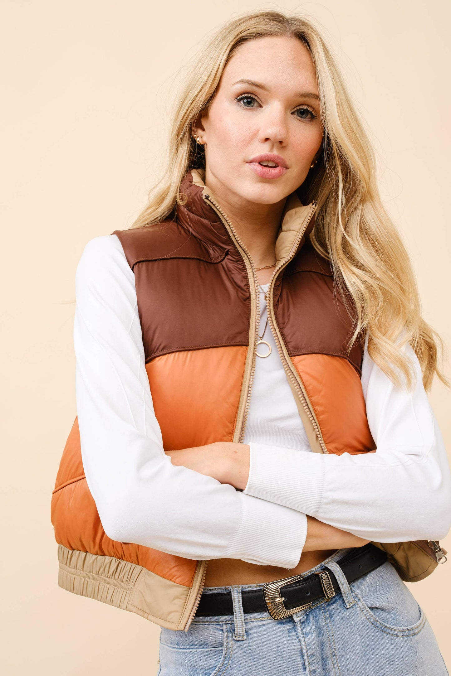 Woman wearing a brown and orange quilted vest on a beige background