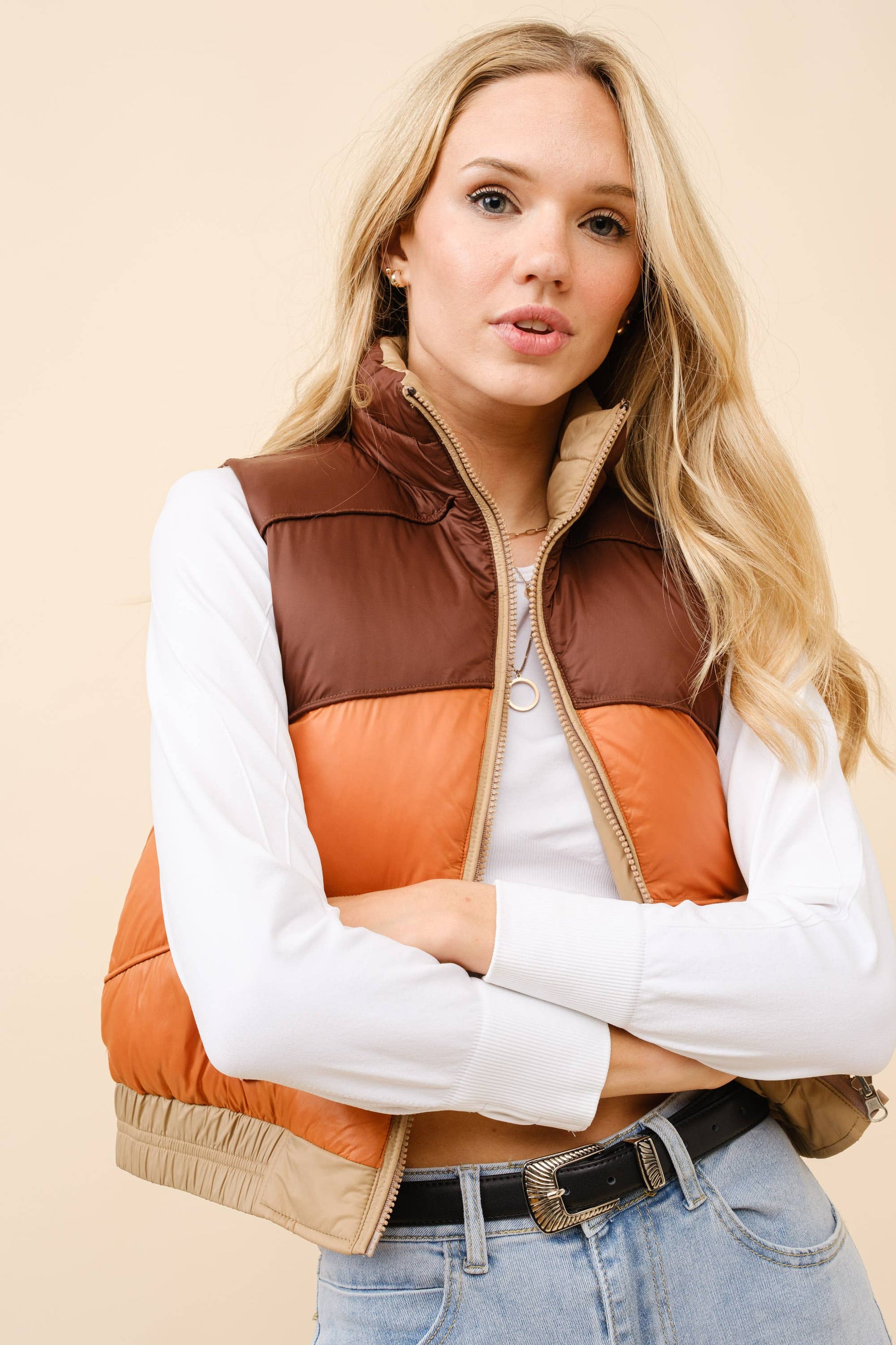 Woman wearing a brown and orange quilted vest on a beige background