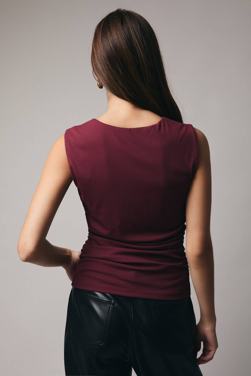 Woman wearing a burgundy sleeveless top against a gray background