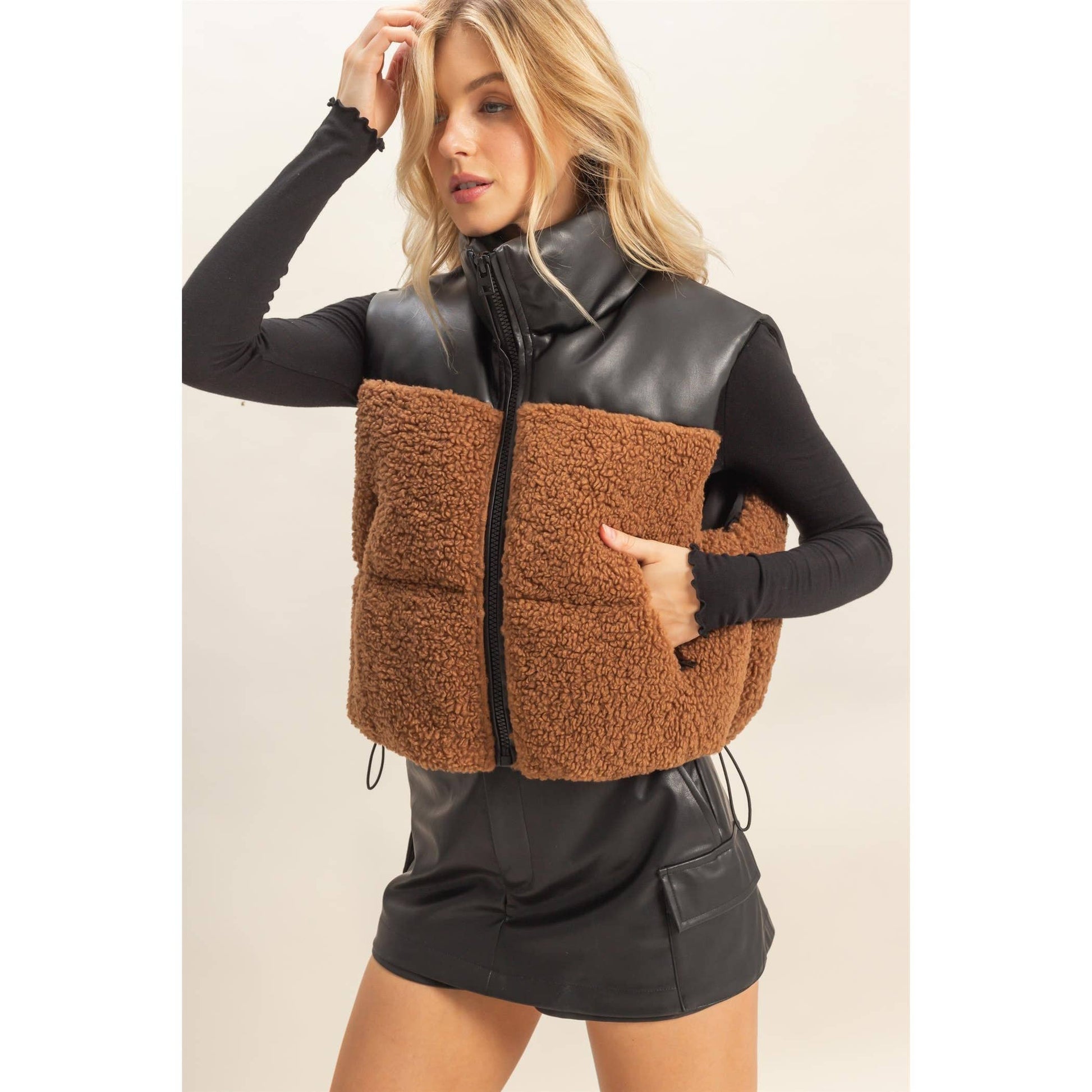 Woman wearing a black and brown quilted vest on a beige background