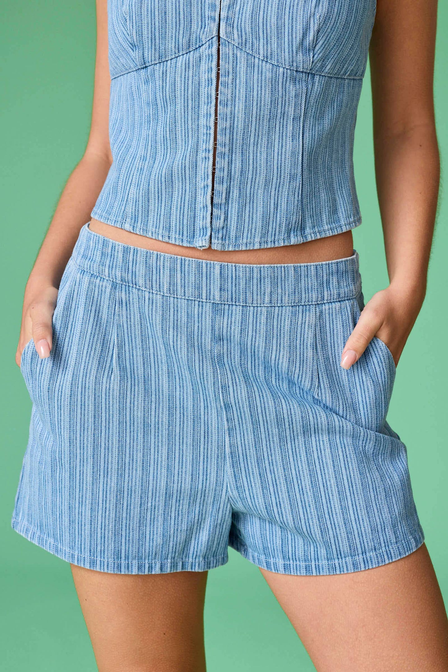 Person wearing a blue striped outfit with shorts and a top against a green background