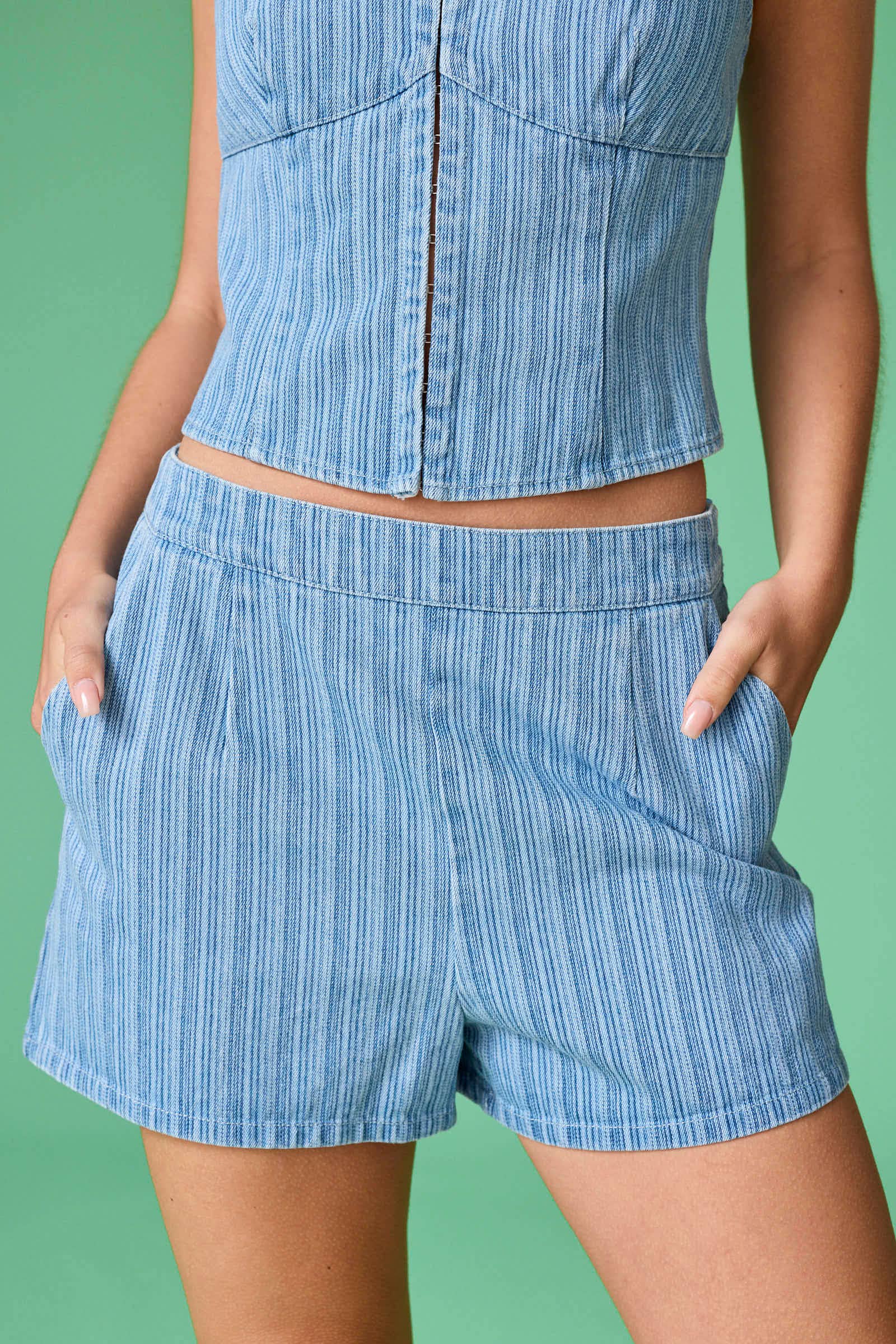 Person wearing a blue striped outfit with shorts and a top against a green background