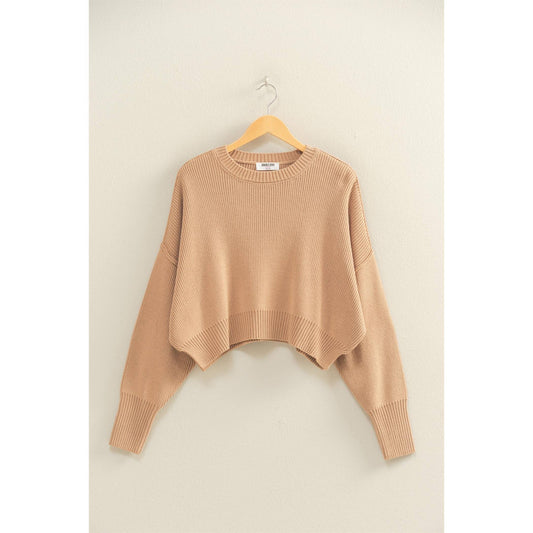 Beige sweater on a hanger against a beige wall
