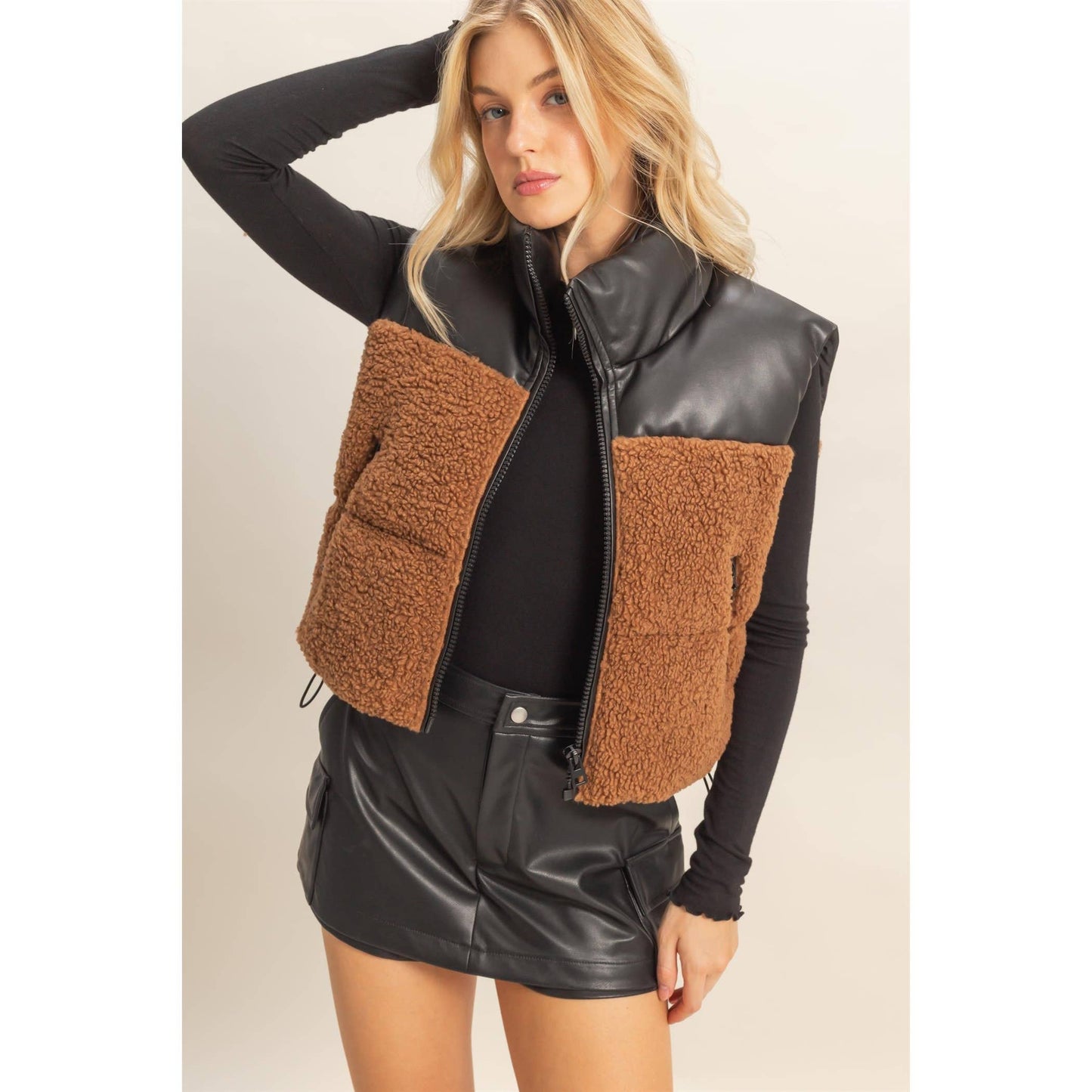 Woman wearing a brown and black quilted vest on a beige background