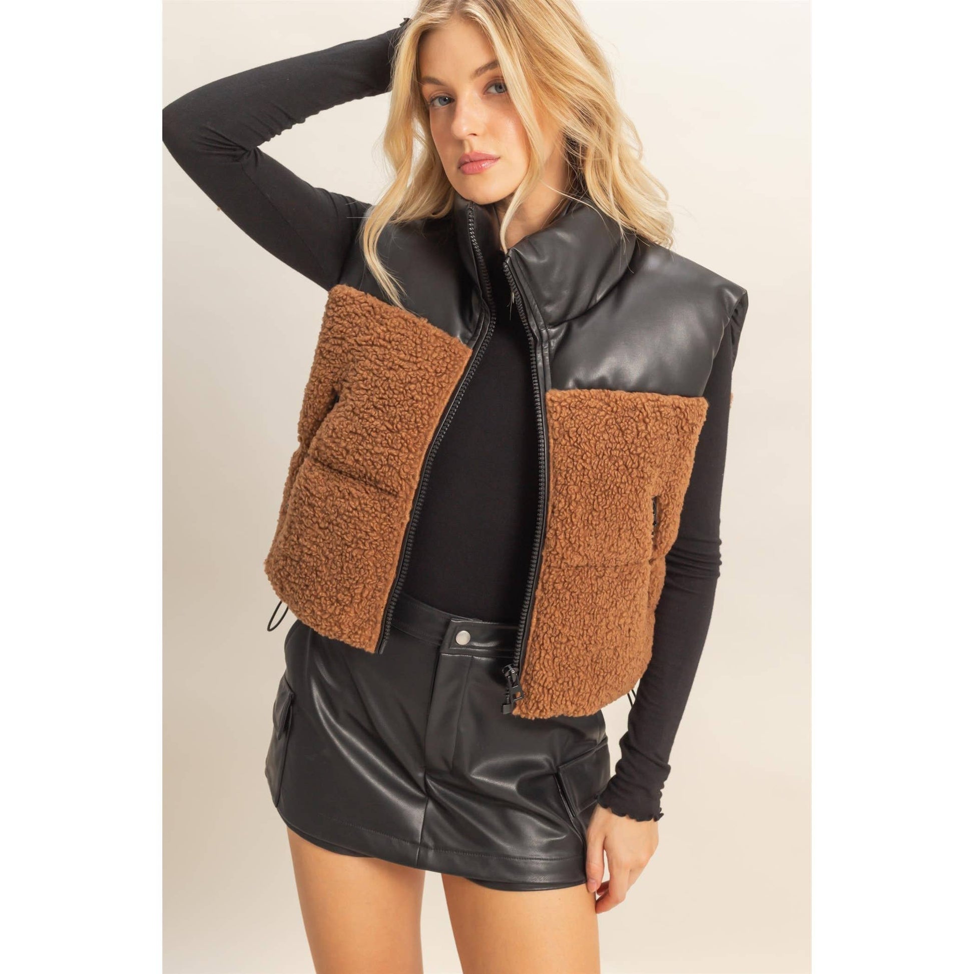 Woman wearing a brown and black quilted vest on a beige background