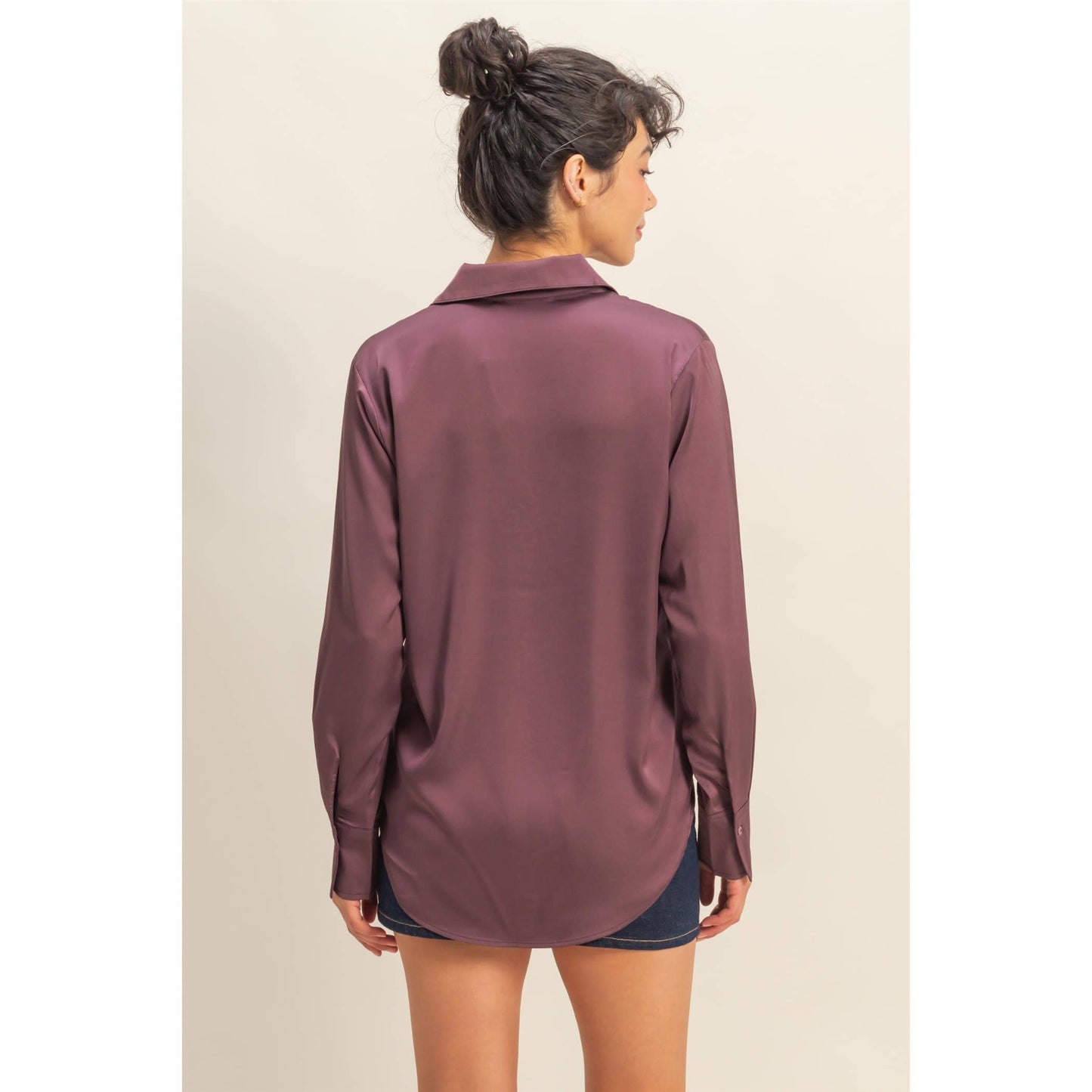 Woman wearing a long-sleeve maroon shirt against a beige background