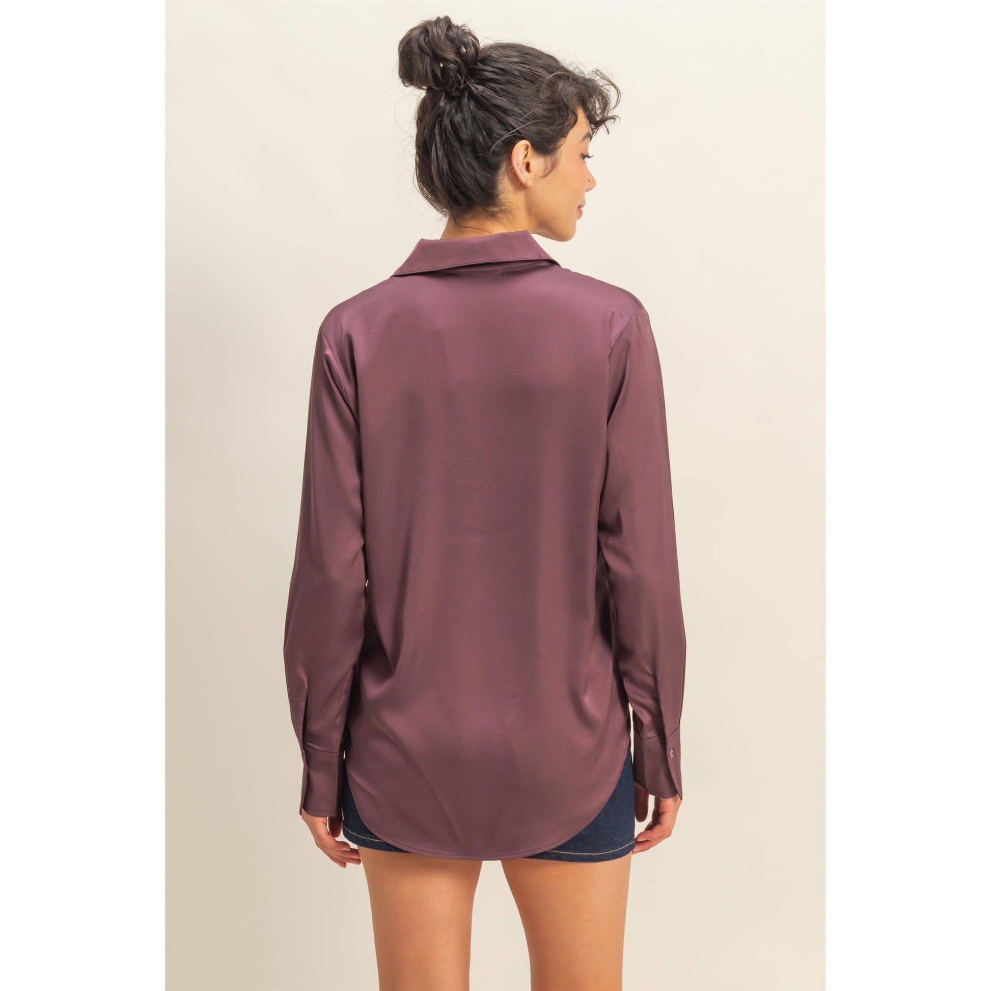 Woman wearing a long-sleeve maroon shirt against a beige background