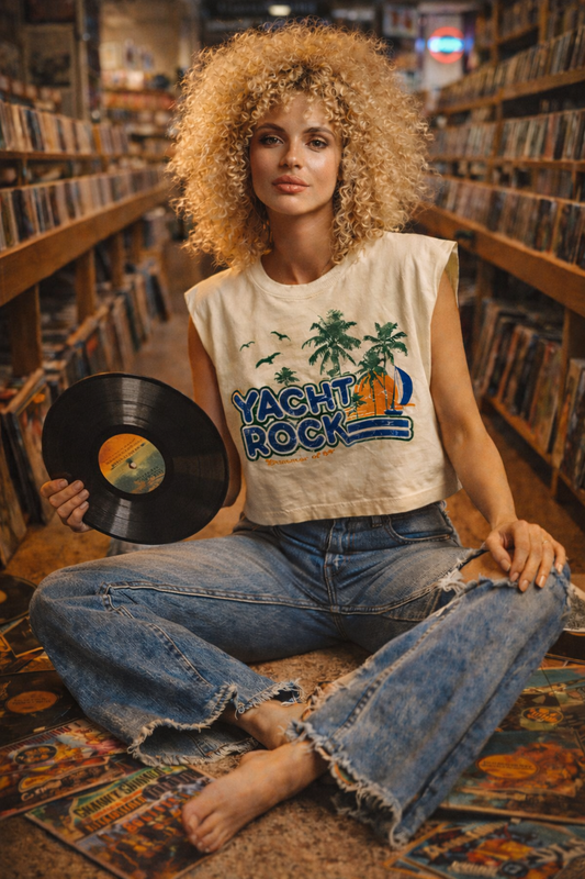 Woman sitting in a record store holding a vinyl record, wearing a 'Yacht Rock' t-shirt.